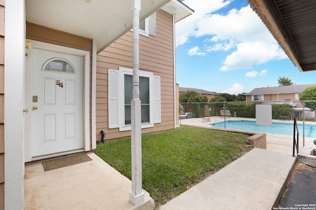 entrance to property with a yard, a fenced in pool, and a patio