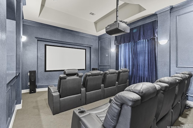 home theater room with a raised ceiling, crown molding, and carpet floors