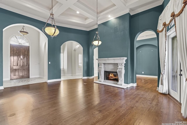 unfurnished living room with a high end fireplace, coffered ceiling, hardwood / wood-style flooring, ornamental molding, and beamed ceiling