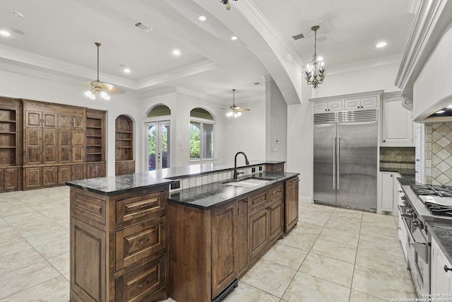 kitchen with white cabinetry, sink, backsplash, an island with sink, and high end appliances