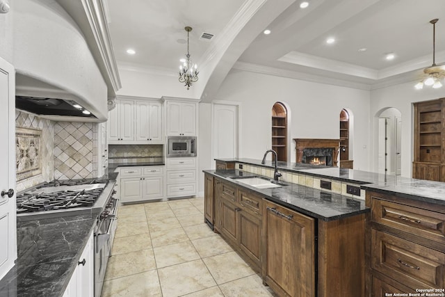 kitchen with premium range hood, stainless steel microwave, white cabinets, and sink