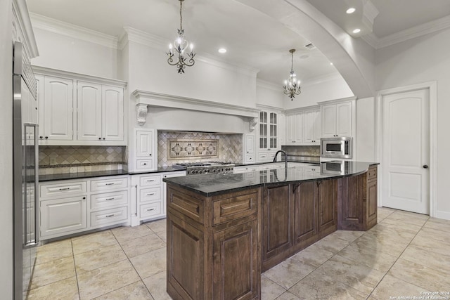 kitchen with backsplash, ornamental molding, built in appliances, white cabinets, and a center island