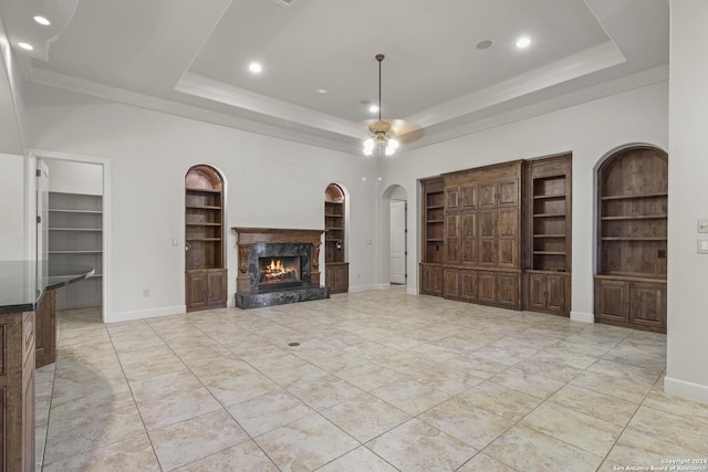 unfurnished living room with a tray ceiling, a premium fireplace, and built in features