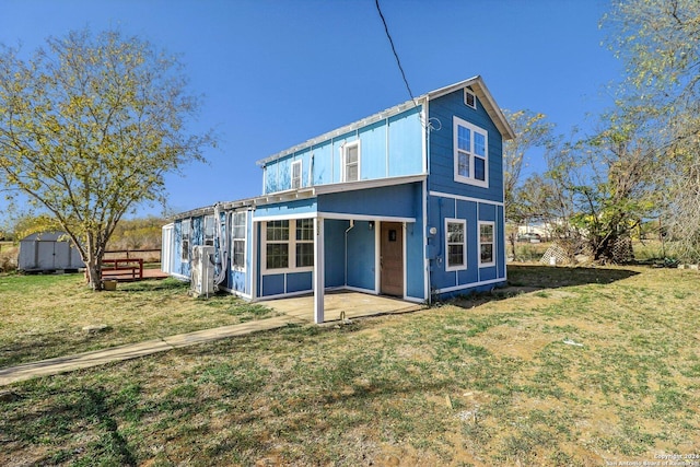 back of property featuring a storage unit, a patio area, and a lawn