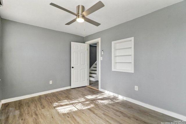 empty room with hardwood / wood-style floors, ceiling fan, and built in features