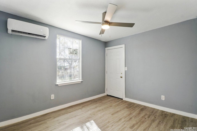 spare room with a wall unit AC, ceiling fan, and light hardwood / wood-style floors