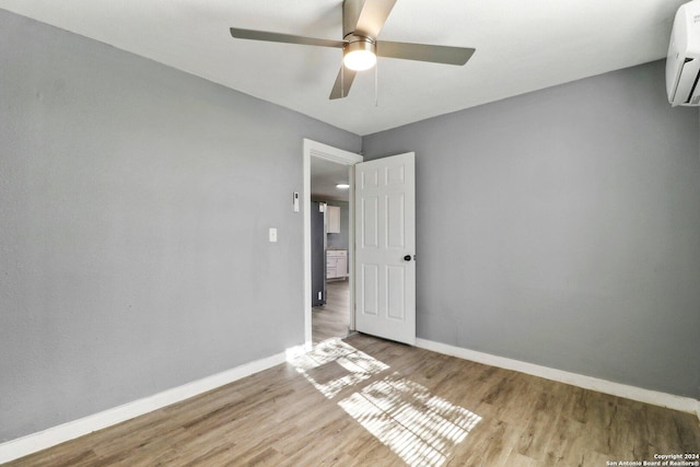 spare room featuring ceiling fan, light wood-type flooring, and a wall mounted AC