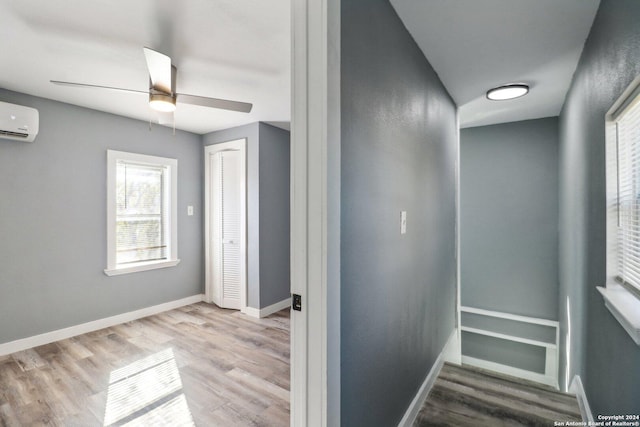 interior space featuring a wall mounted air conditioner, ceiling fan, and wood-type flooring