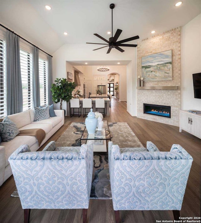 living room with a fireplace, dark hardwood / wood-style floors, ceiling fan, and lofted ceiling