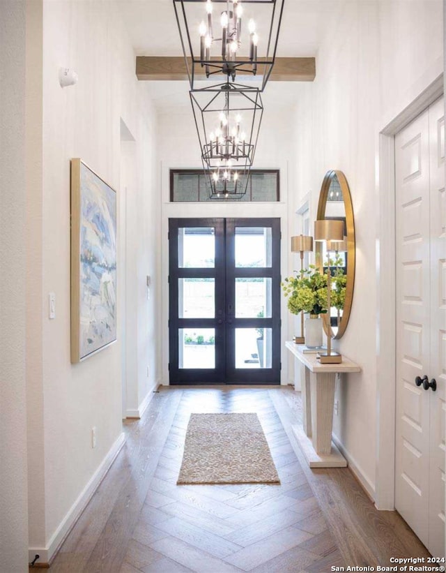 entryway with french doors, beamed ceiling, light hardwood / wood-style floors, and an inviting chandelier