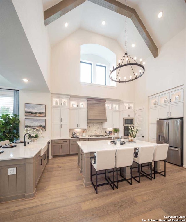 kitchen featuring white cabinetry, stainless steel appliances, high vaulted ceiling, premium range hood, and pendant lighting