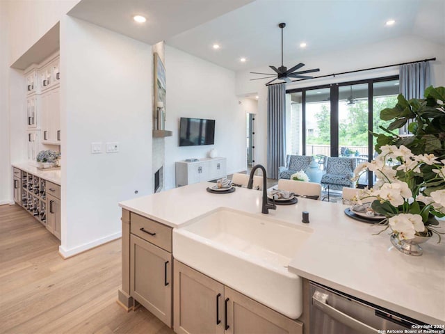 kitchen featuring dishwasher, lofted ceiling, sink, ceiling fan, and light wood-type flooring