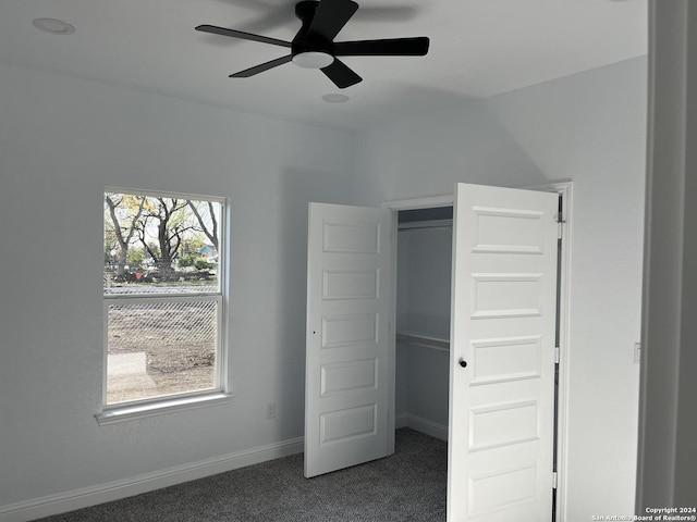 unfurnished bedroom featuring ceiling fan and dark colored carpet