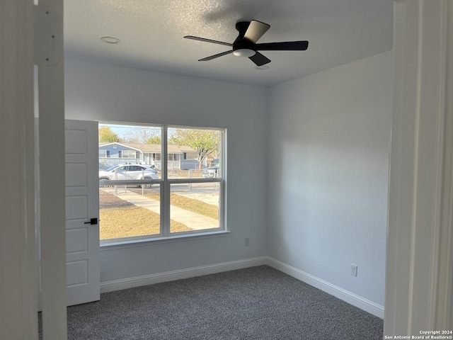 carpeted empty room featuring ceiling fan and a textured ceiling