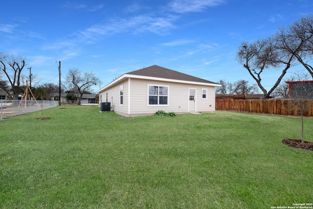 back of house featuring central AC unit and a lawn