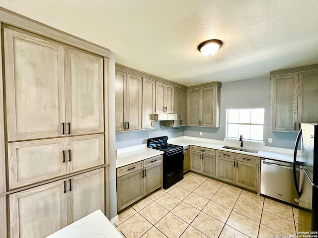 kitchen featuring a textured ceiling, sink, light tile patterned floors, and stainless steel appliances