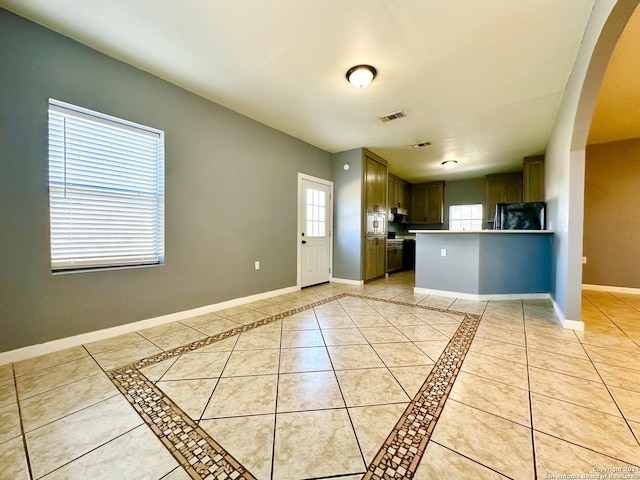 kitchen featuring light tile patterned flooring, a healthy amount of sunlight, built in microwave, and fridge