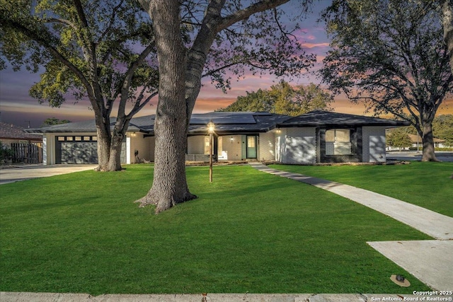 view of front of property with a garage, a yard, and solar panels