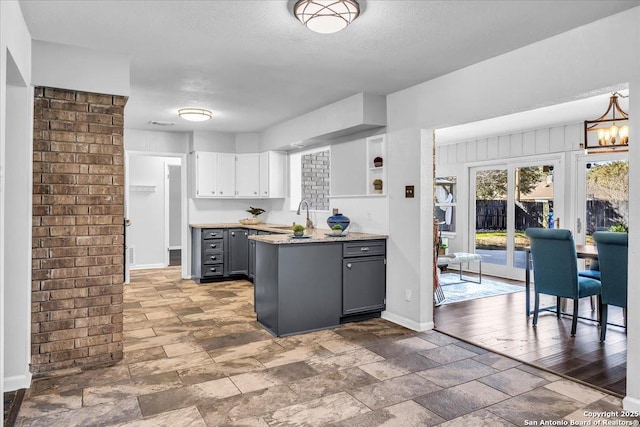 kitchen with sink, gray cabinets, white cabinetry, an inviting chandelier, and a textured ceiling