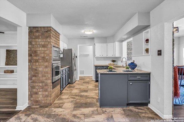 kitchen with sink, appliances with stainless steel finishes, white cabinetry, gray cabinetry, and a wealth of natural light