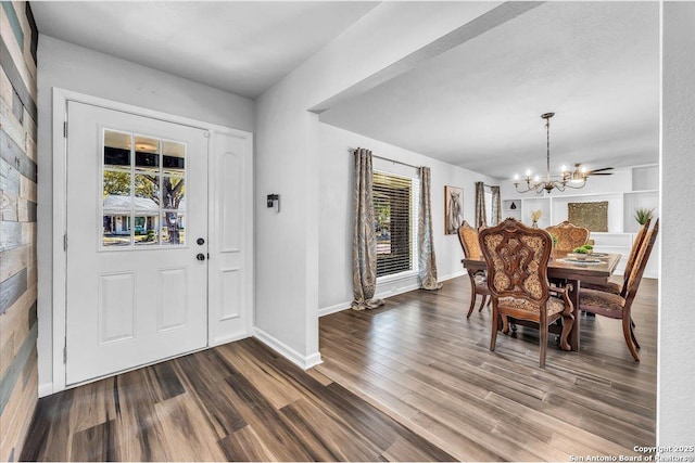 foyer entrance with an inviting chandelier and dark hardwood / wood-style flooring