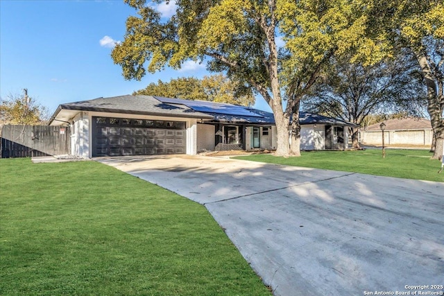 view of front of property featuring a garage, a front lawn, and solar panels