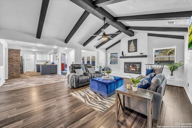 living room featuring a brick fireplace, lofted ceiling with beams, hardwood / wood-style floors, and ceiling fan