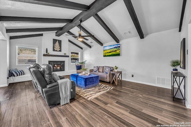 living room with plenty of natural light, a brick fireplace, and vaulted ceiling with beams