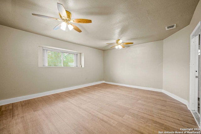 spare room with a textured ceiling and light hardwood / wood-style flooring