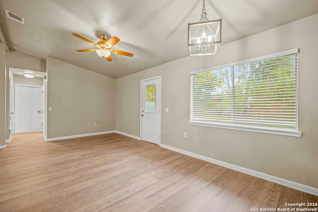 unfurnished room with ceiling fan with notable chandelier and light hardwood / wood-style floors