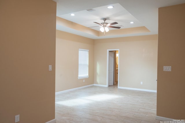 empty room featuring a tray ceiling and ceiling fan