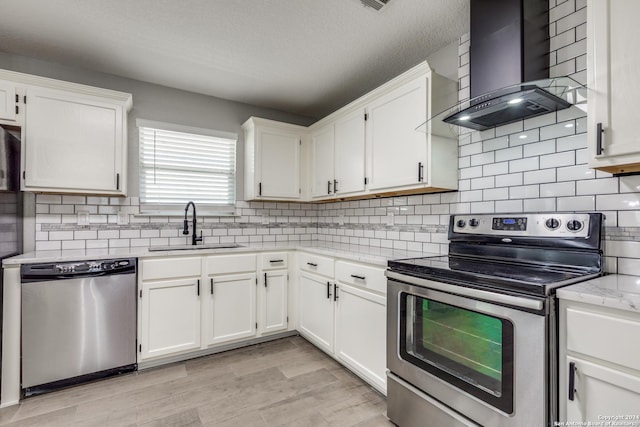 kitchen featuring stainless steel appliances, white cabinetry, wall chimney exhaust hood, and sink