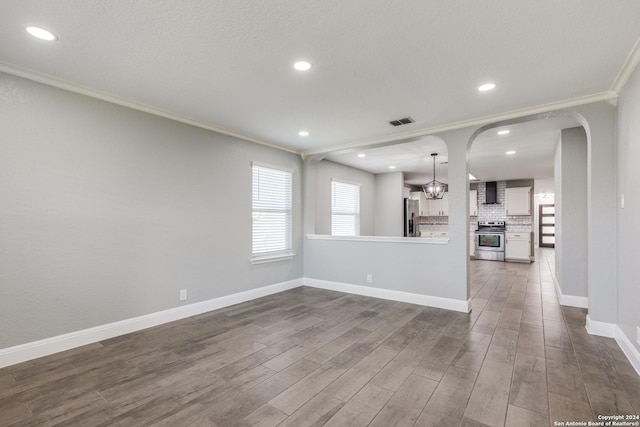 unfurnished living room featuring a notable chandelier, dark hardwood / wood-style floors, and ornamental molding