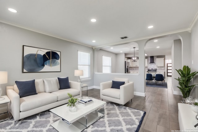 living room featuring hardwood / wood-style floors, a notable chandelier, and crown molding