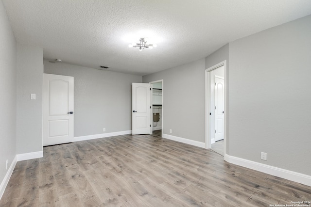 empty room with a textured ceiling and light wood-type flooring