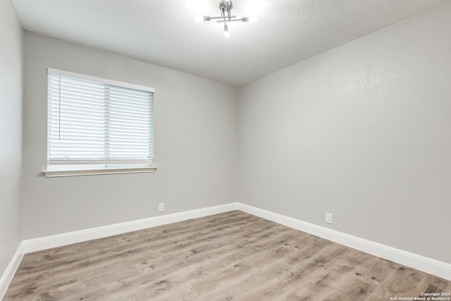 unfurnished room with a textured ceiling and light wood-type flooring