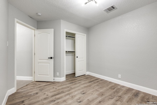 unfurnished bedroom featuring a closet, light hardwood / wood-style floors, and a textured ceiling