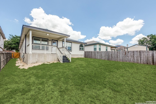 back of property featuring covered porch and a yard