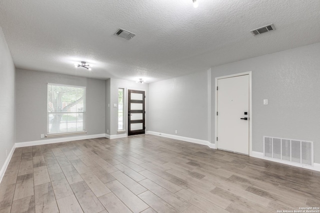 unfurnished room featuring light hardwood / wood-style flooring and a textured ceiling