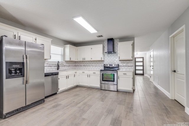 kitchen featuring tasteful backsplash, white cabinets, wall chimney exhaust hood, and stainless steel appliances