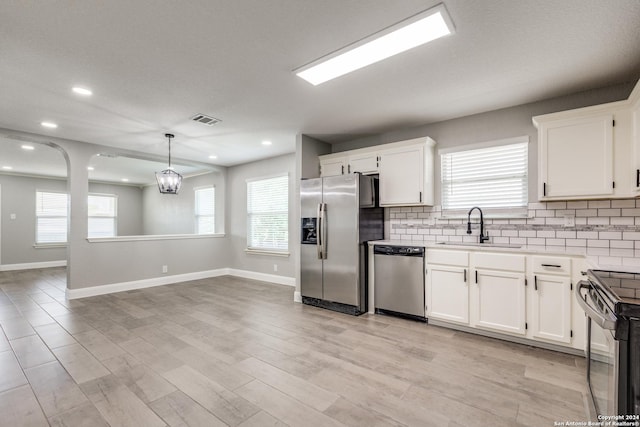 kitchen featuring white cabinetry, sink, hanging light fixtures, an inviting chandelier, and appliances with stainless steel finishes