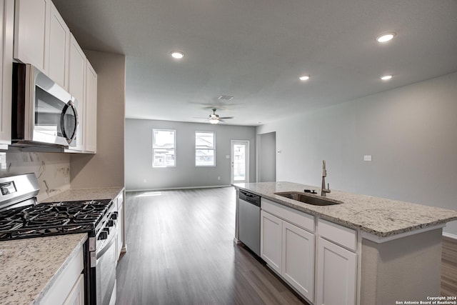 kitchen featuring backsplash, stainless steel appliances, a kitchen island with sink, sink, and white cabinets