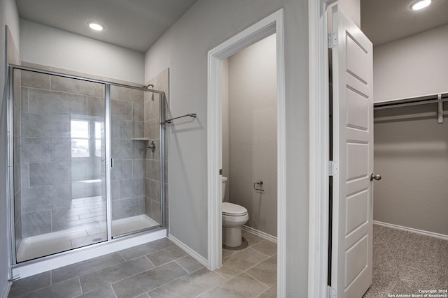 bathroom featuring a shower with door, tile patterned flooring, and toilet