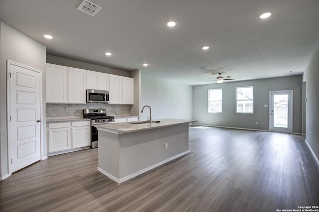 kitchen with appliances with stainless steel finishes, tasteful backsplash, a kitchen island with sink, sink, and white cabinets