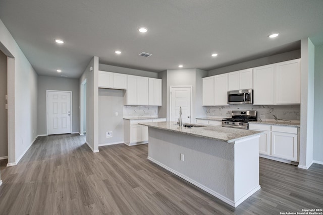 kitchen featuring white cabinets, stainless steel appliances, and a kitchen island with sink