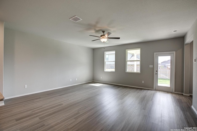 empty room with ceiling fan, dark wood-type flooring, and a textured ceiling