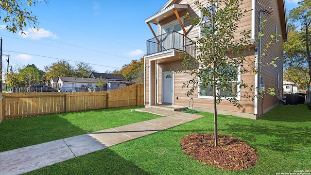 view of front of property with central AC unit, a balcony, and a front yard