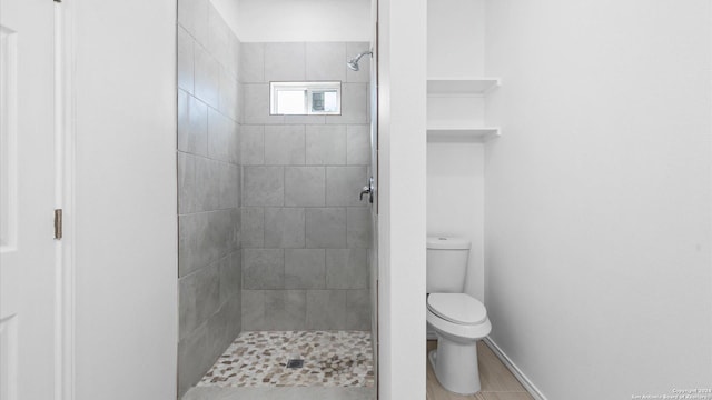 bathroom featuring a tile shower, toilet, and tile patterned floors