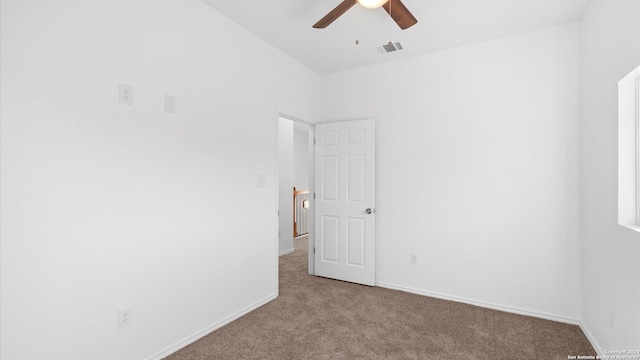 carpeted spare room with ceiling fan