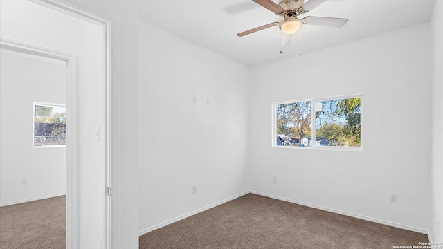 carpeted spare room featuring ceiling fan and a healthy amount of sunlight